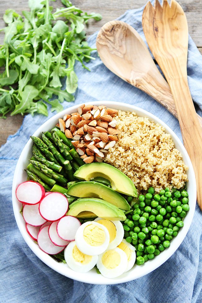 Assiette composée de quinoa, avocat, asperges, radis, petits pois, œufs et amandes